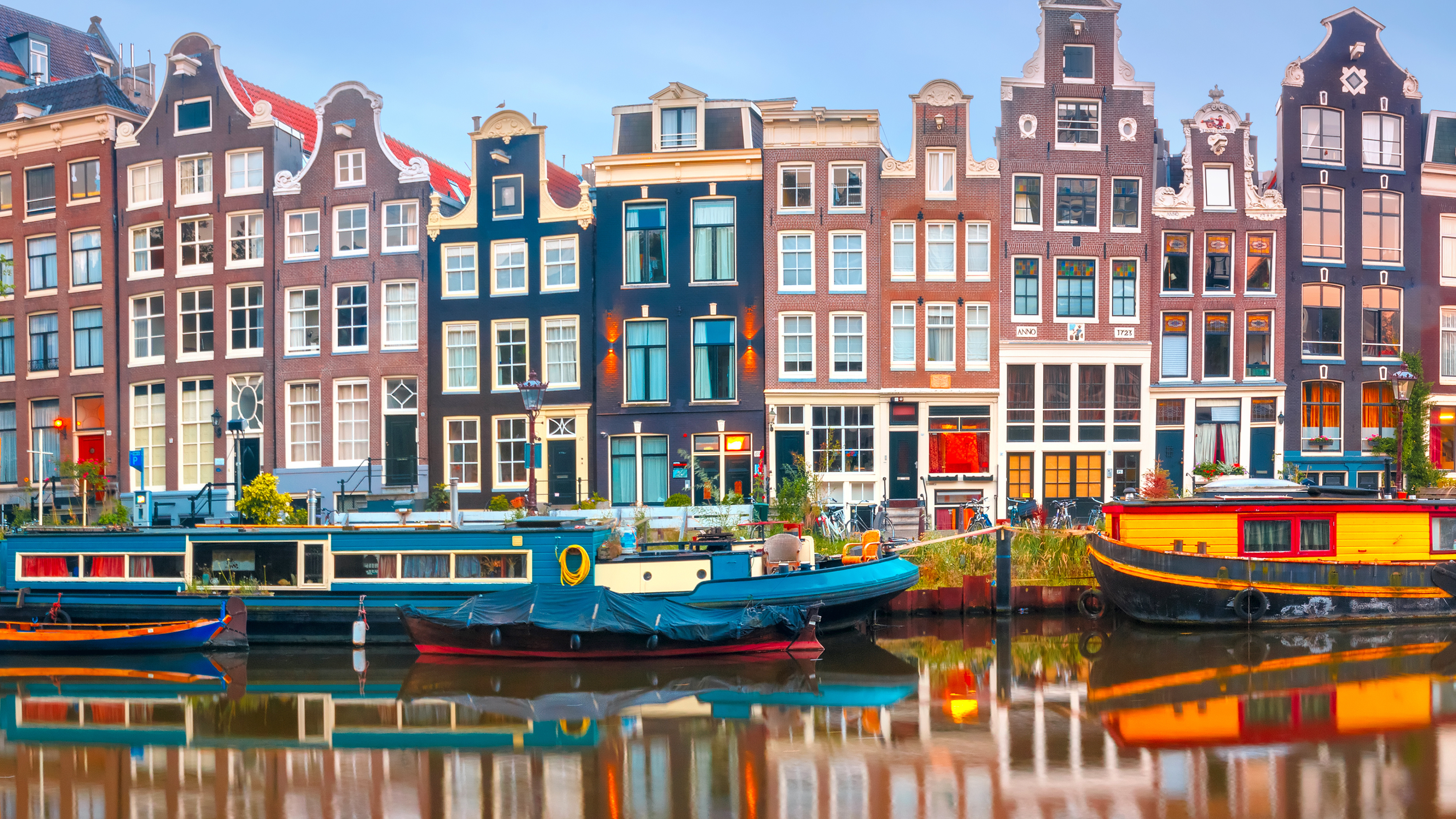 row Amsterdam buildings canal boats reflection foggy morning colorful